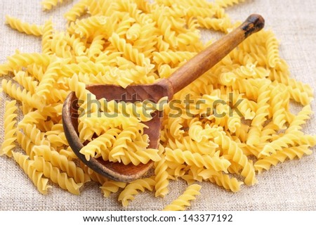 raw pasta or macaroni and wooden spoon