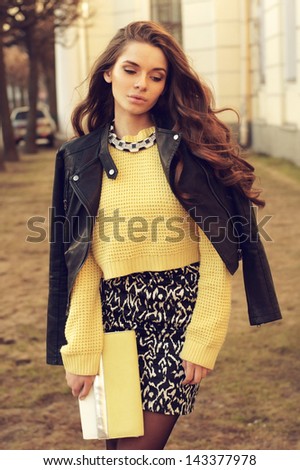 Young Beautiful Woman Wearing Dress, Yellow Pullover And Leather Jacket Posing Outdoors. Stylish Fashion Portrait