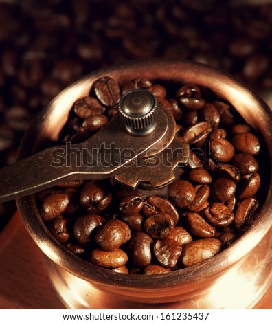 closeup of manual coffee grinder with coffee beans against coffee beans background