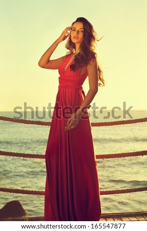 young beautiful elegant woman in pink dress standing near sea