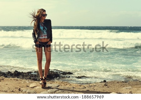 Beautiful tall slim stylish girl at stormy ocean coast. Sexy fashion portrait.