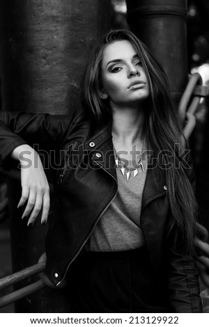 outdoor stylish fashion portrait. young beautiful girl with long hair wearing black clothes. black leather jacket and skirt