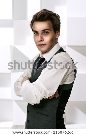 Fashion style studio portrait of young successful man dressed in stylish classic clothes with necktie with crossed arms and looking in camera