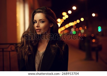 Sexy gorgeous brunette girl portrait in night city lights. Vogue fashion style portrait of young pretty beautiful woman with long dark curly hair. Shallow DOF