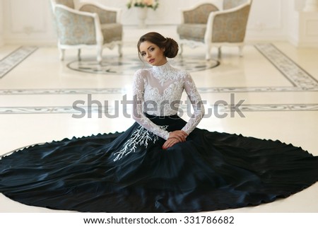 Beautiful elegant girl in expensive evening dress sitting on floor in luxury white interior