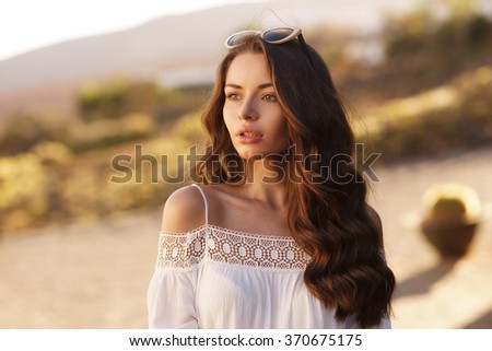 Young beautiful pretty woman with clean skin and long curly brunette hair looking away.