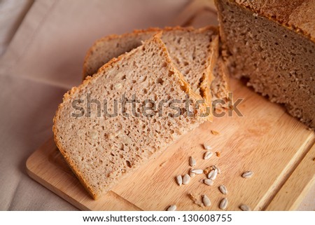 Sliced dark bread with crumbs on sacking background