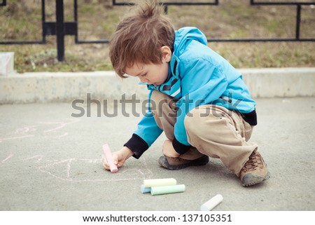 Boy drawing on road. Outdoor.