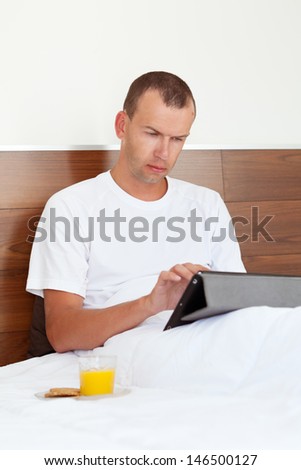 Portrait of man using tablet computer in bedroom