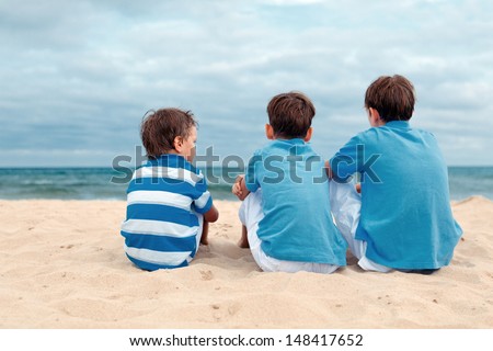 Three brothers are sitting on beach, outdoor