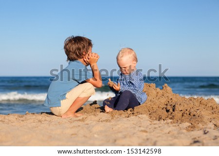 Happy brother and sister playing in the sand at the beach