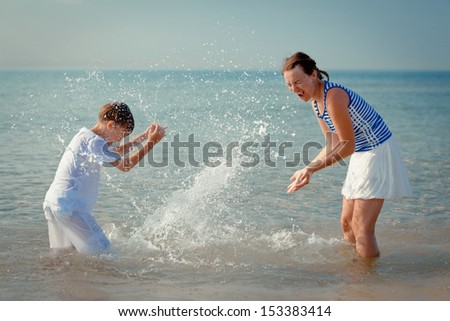 Mom and son splashing water at sea, outdoor