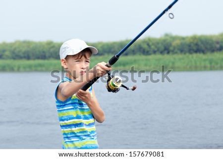 serious boy fishing on river, summer