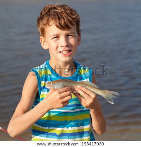 Young boy holding fish and smiling