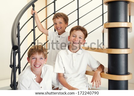 Three happy brother sitting on steps, indoor