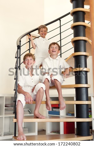 Three happy brother sitting on steps, indoor