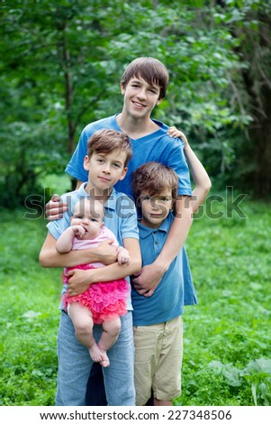 Portrait of three happy brothers and sisters in summer park