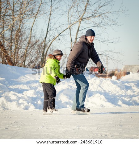 Happy fun father and son learning to skate, winter, outdoor