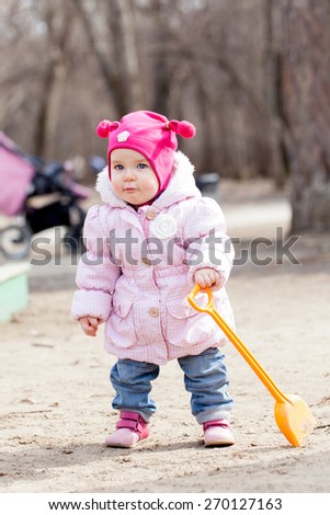 Happy cute baby girl walks in spring park, first steps