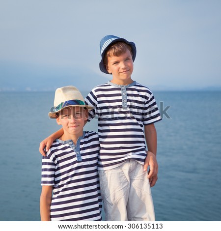 Two happy brothers hug and look at ships, yacht at sea