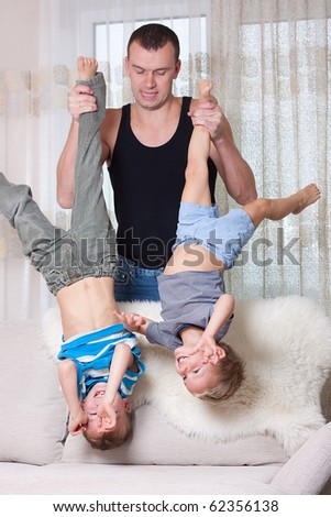 Father holding his two sons upside down.