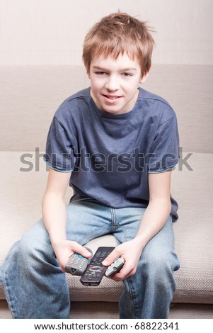Teen watches television and holds three remote in room
