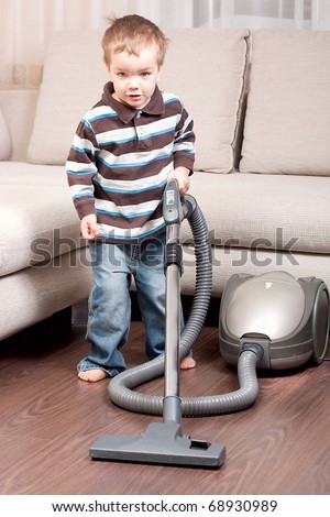 Small boy with vacuum cleaner in room