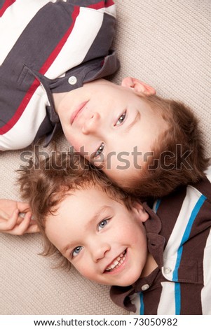 Two happy brothers lie on couch, indoor