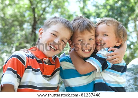 Three merry brothers hugging, in park