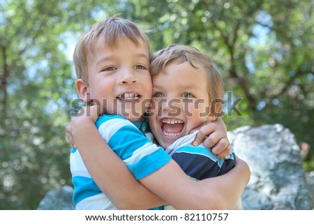 Two merry brothers hugging, in park