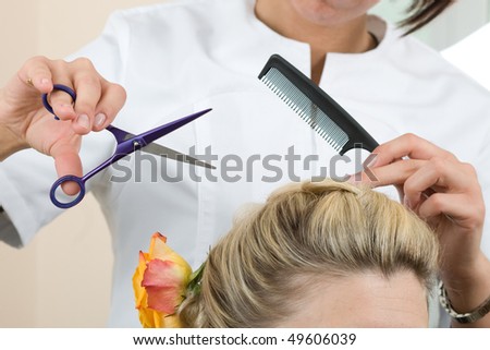Hairdresser makes hair young women by scissors and comb