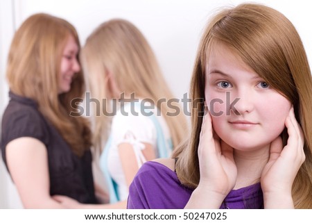The girl looks into the camera. Two girls in the background laughing.