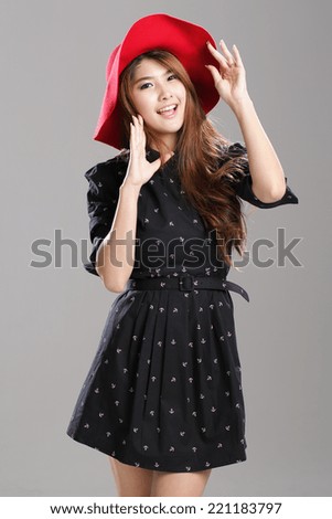 Asian woman posing in anchor printed long sleeve, wrapped waist dress with belt and red hat.