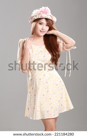 Asian woman posing in yellow shade graphic printed half peplum sleeve, wrapped waist dress with  hat.