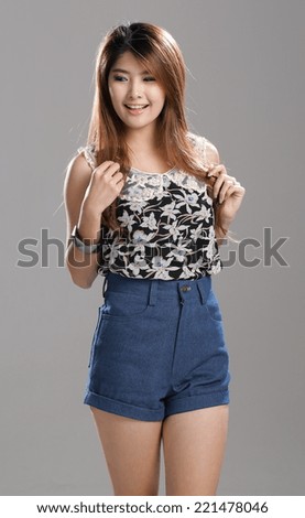 Asian Woman posing in Round Neck Sleeveless Orchid Print Top and high waisted denim shorts with  bracelet.