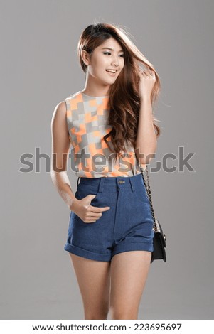 Asian Woman posing in Round Neck Sleeveless Orchid Print Top and high waist denim shorts with bracelet.