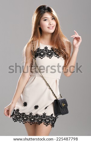 Asian woman posing in  Pleated Sleeveless Lace Stripe Hem Dress with black sling bag.