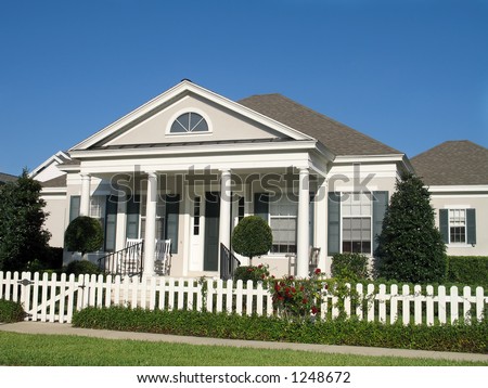 charming small town America cottage with picket fence around a lush lawn