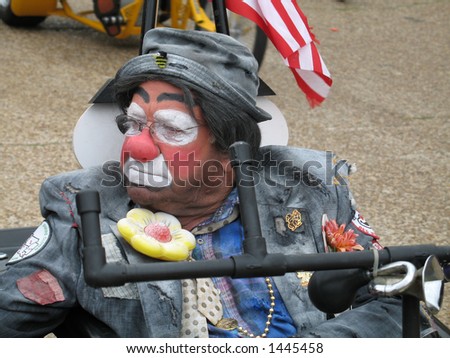 a Shriner clown drives his little cart in a small town festival parade