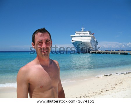 young man on the beach at Grand Turk, British West Indies, with cruise ship at dock in background