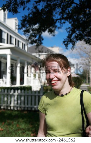 smiling teenage girl walking down street in front of houses in small town America