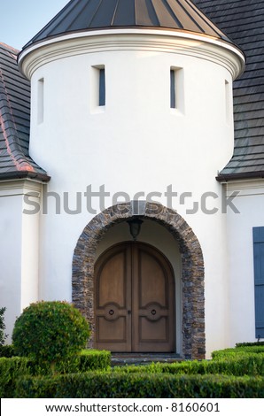 an arched entry bordered with stone leads to the front doorway of an upscale home