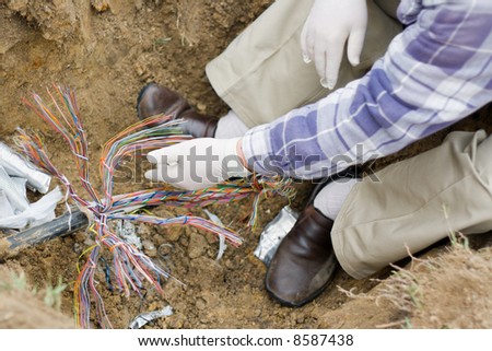 a technician repairs an underground telephone line