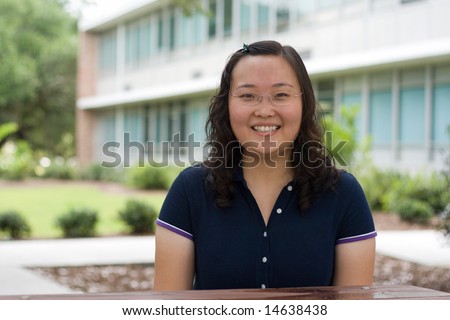 a pretty, smiling Chinese college student outside a classroom building