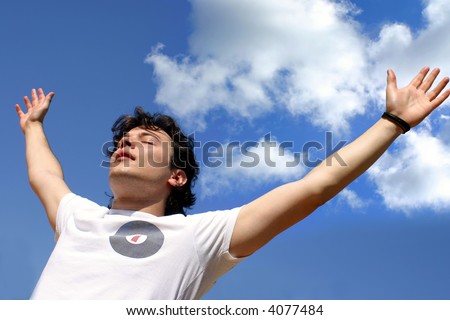 young man with open arms over sky background