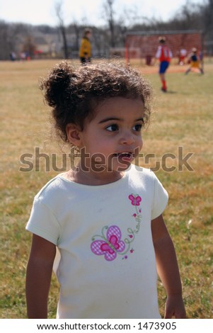 Two year old girl outside at a soccer game.