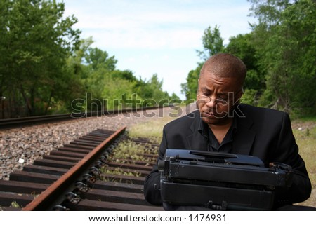 Young man with his typewriter on the train tracks.