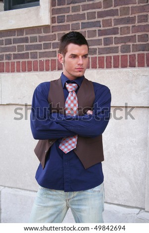 Young man posing while leaning on a wall outside
