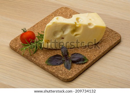 Maasdam cheese on the board with rosemary and mint