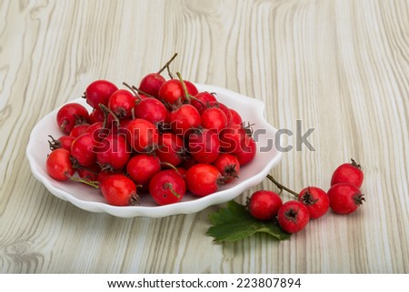 Hawthorn berries in the bowl on wood background